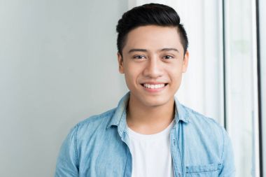 Asya genç adam pencerede evde ayakta portresi