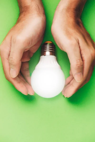 Mãos que protegem a lâmpada eco economizadora de energia fechar — Fotografia de Stock