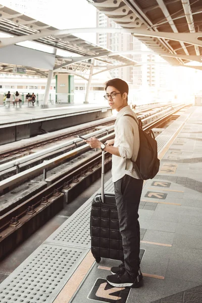 Homme est sur la gare avec sac de voyage, en utilisant un téléphone mobile , — Photo