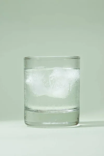 Hielo vaso de agua potable en la mesa sobre verde . — Foto de Stock