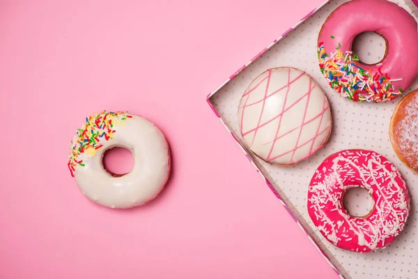 Munkar med glasyr på pastellrosa bakgrund. Söta munkar. — Stockfoto