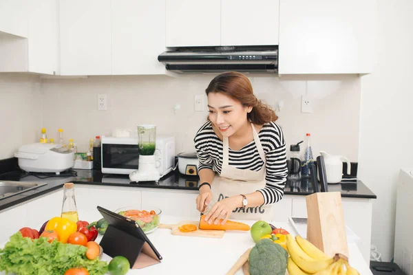 Mooie Aziatische vrouw koken volgens recept op tablet scre — Stockfoto