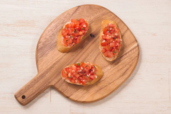 Sencilla bruschetta italiana apetitosa con tomate, sobre tabla de madera —  Fotos de Stock