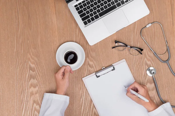 Top uitzicht op volwassen arts werkzaam met Klembord op zijn bureau en — Stockfoto