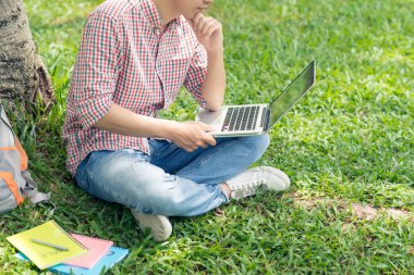 Park Çimenlikte oturan ve kucağına çalışma öğrenci Resim kırpılmış