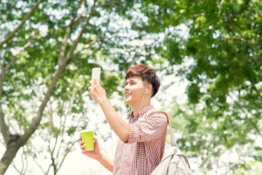 Genç gülümseyen adam alarak resim city bölgesindeki yürürken.
