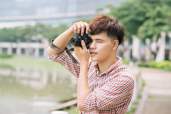 Junger lächelnder Mann beim Fotografieren während er durch die Stadt läuft. — Stockfoto