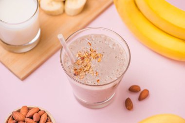 Pembe arka plan üzerine bir bardak taze yapılmış muz smoothie