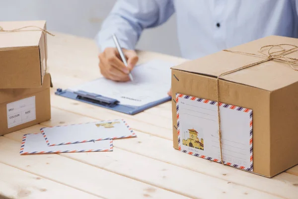 Mensajería haciendo notas en el recibo de entrega entre paquetes en la mesa — Foto de Stock