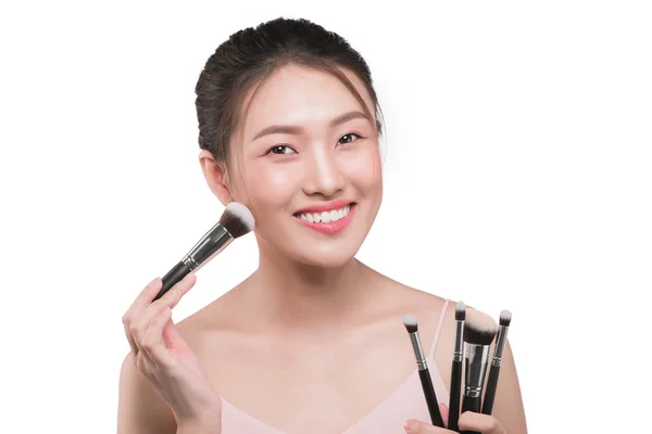 Красивая женщина с косметическими инструментами для макияжа рядом с лицом . — стоковое фото