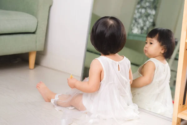 Маленькая милая азиатская девочка сидит на полу и играет — стоковое фото