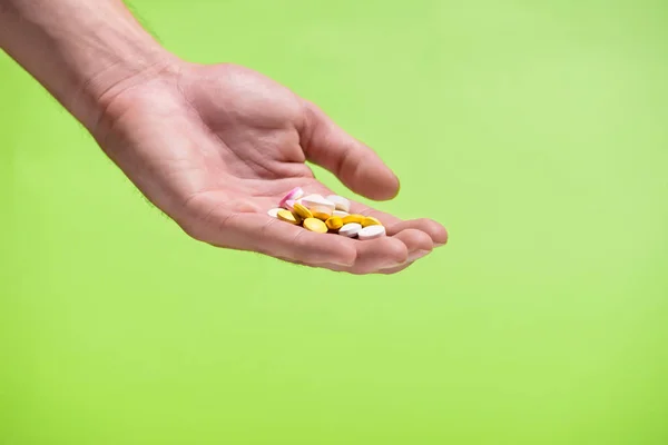 Кольорові таблетки в руці на зеленому тлі . — стокове фото