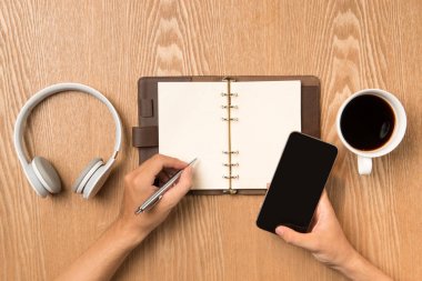 Masada oturan defter üzerinde yazılı dostum, akıllı pho tutan el