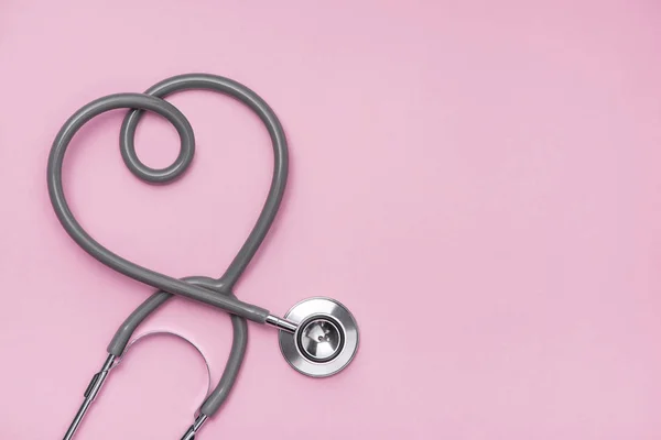 Concepto médico. El estetoscopio con forma de corazón sobre fondo rosado — Foto de Stock