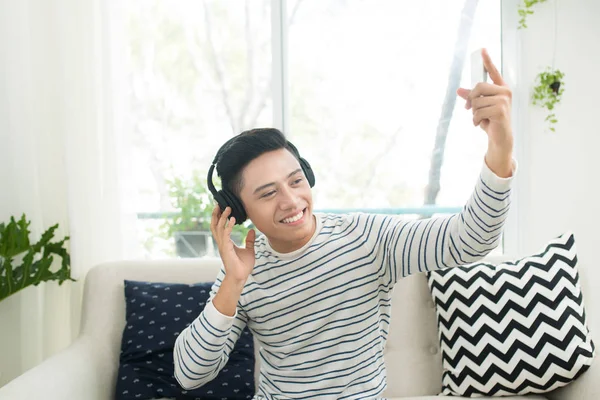 Homem em fones de ouvido sentado no sofá — Fotografia de Stock