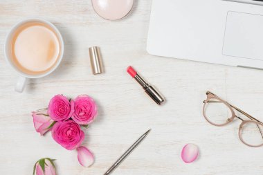 ruj, gözlük. dizüstü bilgisayar, kalem ve çay 