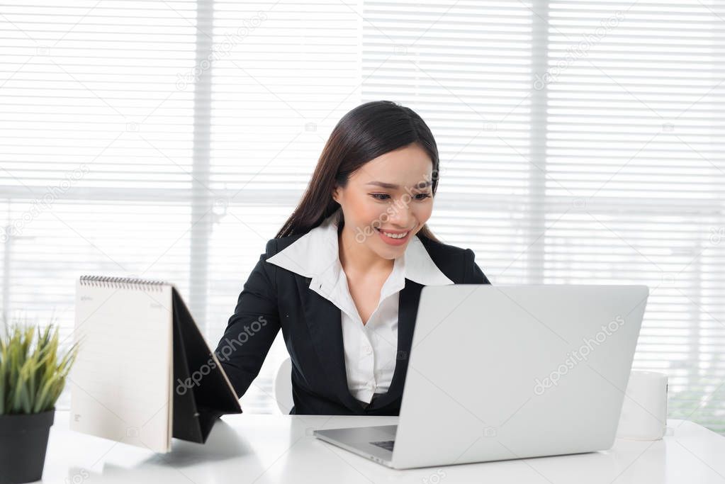 Confident asian businesswoman sitting at desk in office