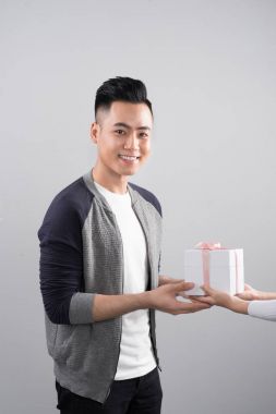 Mutlu aşk hediye kutusu ile gri arka plan üzerinde duran genç çift gülümseyen