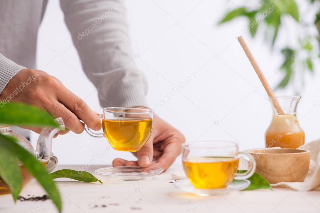 Hand holding cup of tea on wooden table background