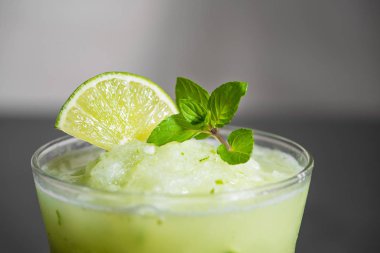 Kokteyl suyu limon, nane ve buz ile. Siyah tablo arka plan üzerinde bar içki aksesuarları.