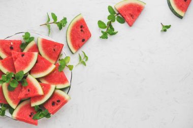 Karpuz dilimleri, beyaz zemin üzerine yeşil nane yaprakları. Üstten Görünüm, düz yatıyordu.