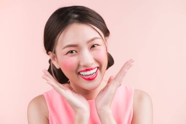 Genç ve güzel sevimli gülümseyen kadın yakın çekim pembe bir arka plan