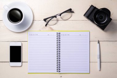 Kalem, gözlük, kahve, kamera, akıllı telefon ve masa üstünde defter. Üstten Görünüm.