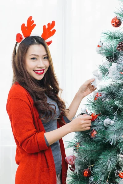 Счастливая молодая азиатка, стоящая у рождественской елки дома — стоковое фото