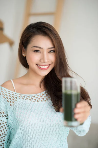 Gülümseyen genç Asyalı kadın yeşil taze sebze suyu içme 