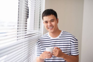 Kahve fincanı tutan pencere rahatlatıcı bir gülümseyen adam portresi