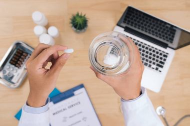 Bir bardak su ve pill tıp tutan doktor kapatın. Sağlık ve tıp kavramı