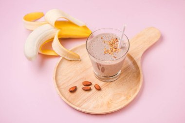 Pembe arka plan üzerine bir bardak taze yapılmış muz smoothie