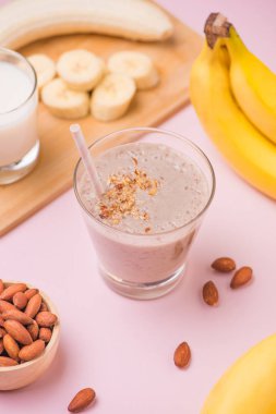 Pembe arka plan üzerine bir bardak taze yapılmış muz smoothie