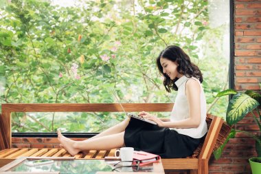 Asyalı kadın yaratıcı office penceresinde yanında otururken dizüstü bilgisayar ile çalışma