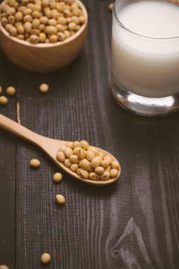 Soya sütü ve soya fasulyesi kase ve ahşap zemin üzerine kaşık ile cam