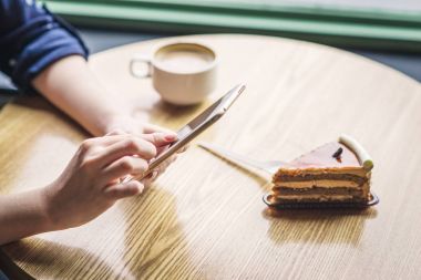 Dijital tablet kullanma ve kahve içmek işkadını kafede masada oturan, kırpma