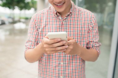 Asya adam akıllı telefon açık havada duran kullanarak