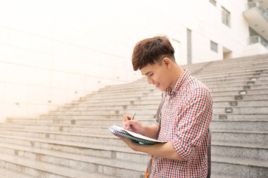 Üniversite Asya erkek öğrenci holding kitapta kampüs