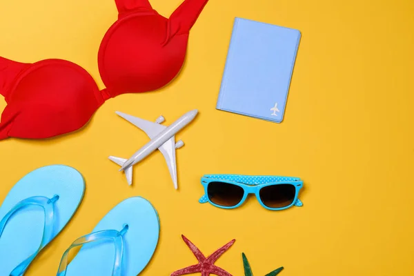 Christmas vacation concept - plane, flip flops, airplane, passport,sunglasses on yellow background