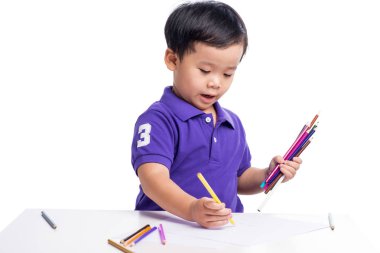 Kalemlerle resim yapan küçük çocuk.