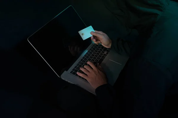 网络犯罪概念 匿名男子手持手提电脑信用卡 — 图库照片