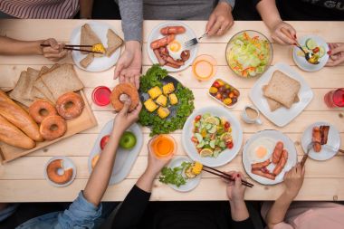 Arkadaşlarınızla akşam yemeği zevk. Grup birlikte ahşap masada otururken yemeğe insan Üstten Görünüm