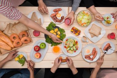 Arkadaşlarınızla akşam yemeği zevk. Grup birlikte ahşap masada otururken yemeğe insan Üstten Görünüm