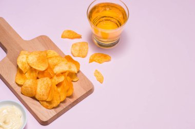 Peynir ve soğan patates cipsi ile alkolsüz içecek pembe bir arka plan üzerinde.