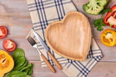 Taze organik sebze ve ahşap kalp disk kopyalama alanı natürmort ile ahşap zemin üzerinde içerir