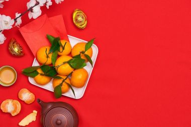 Üstten Görünüm Aksesuar Çin yeni yılı festival süsleri. portakal, yaprakları, ahşap sepeti, kırmızı zemin üzerine kırmızı paket.