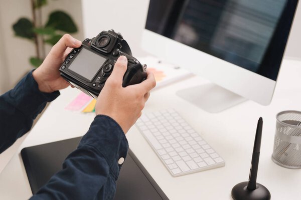 Male photographer, sitting at his desk, looking to camera