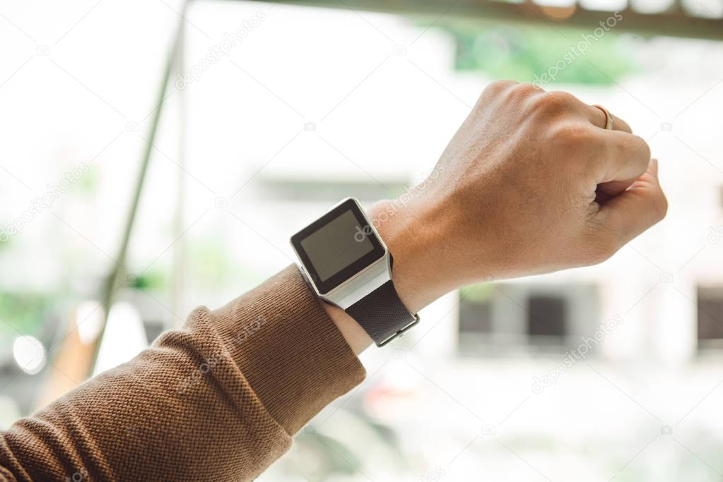 Young man wears smart watch working on table