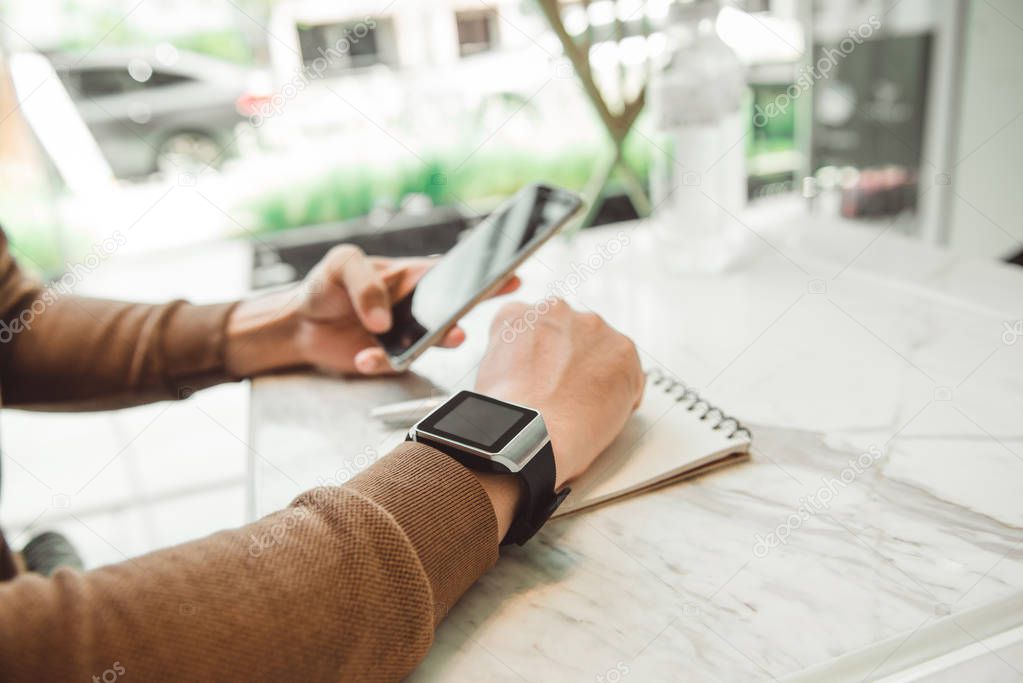 Young man wears smart watch working on table