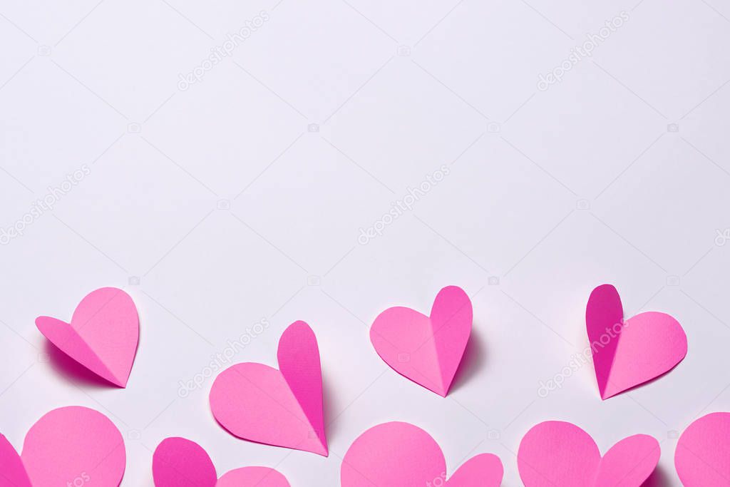 Beautiful pink paper hearts on white paper background